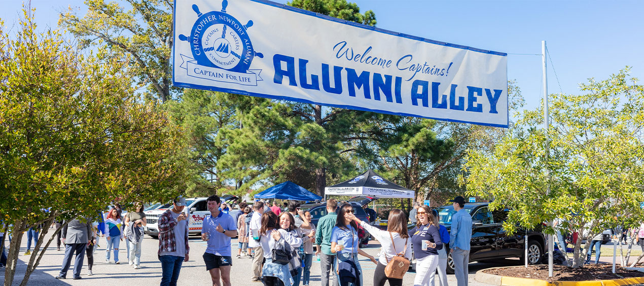 Alumni alley banner with people greeting each other underneath